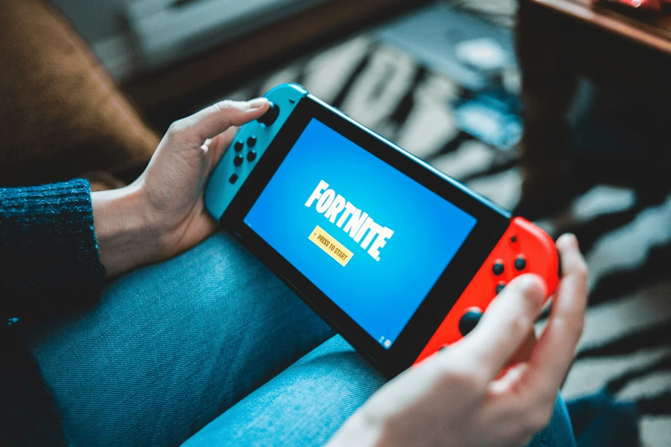 Afbeelding van persoon die Nintendo Switch vasthoudt terwijl hij/zij Fortnite speelt